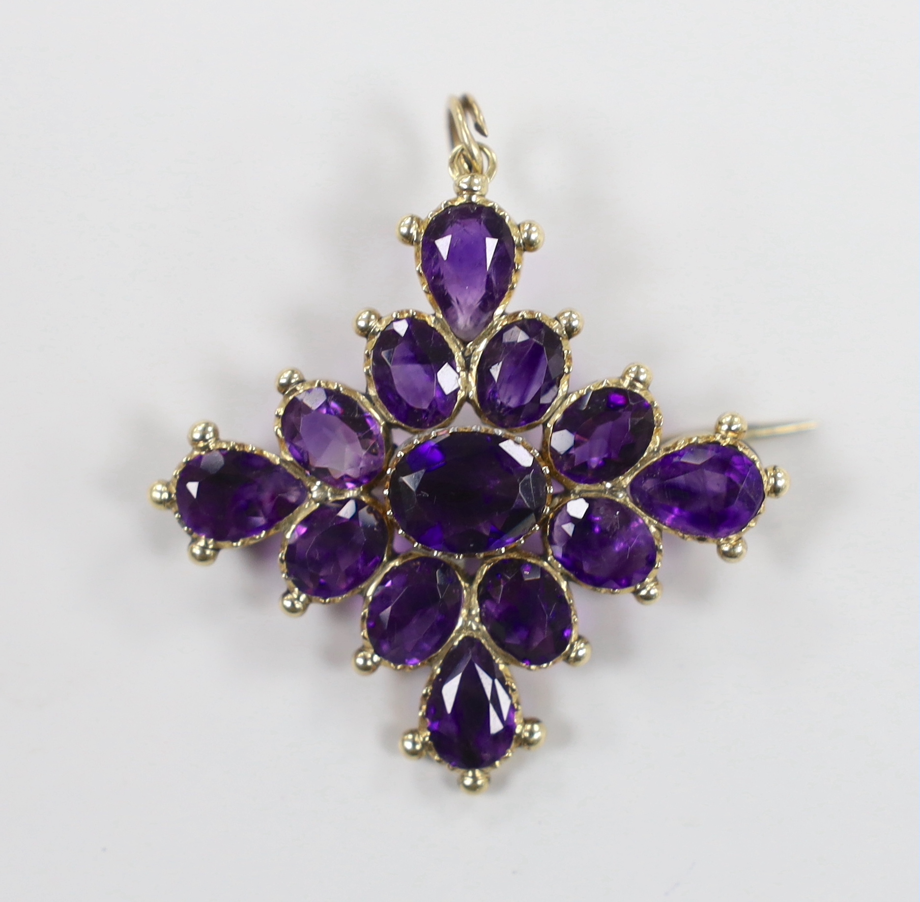 An early 20th century yellow metal and amethyst cluster set quatrefoil pendant brooch, 42mm, gross weight 7.5 grams.